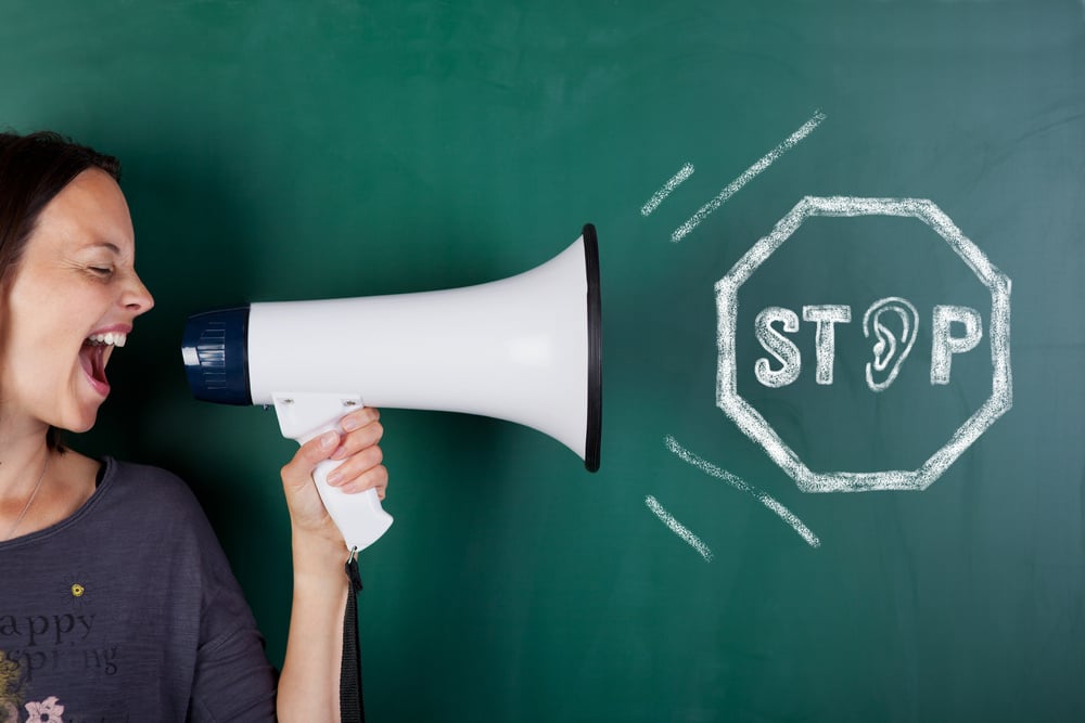 Closeup of woman shouting though megaphone with stop sign drawn on blackboard